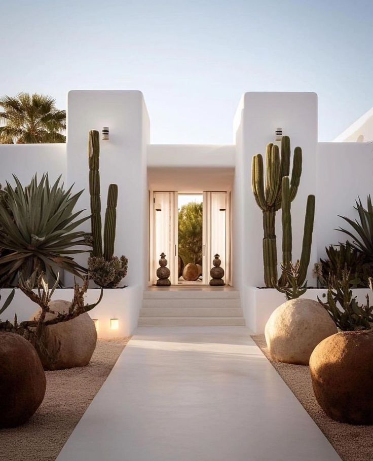 a white house with cactus and rocks in the front yard