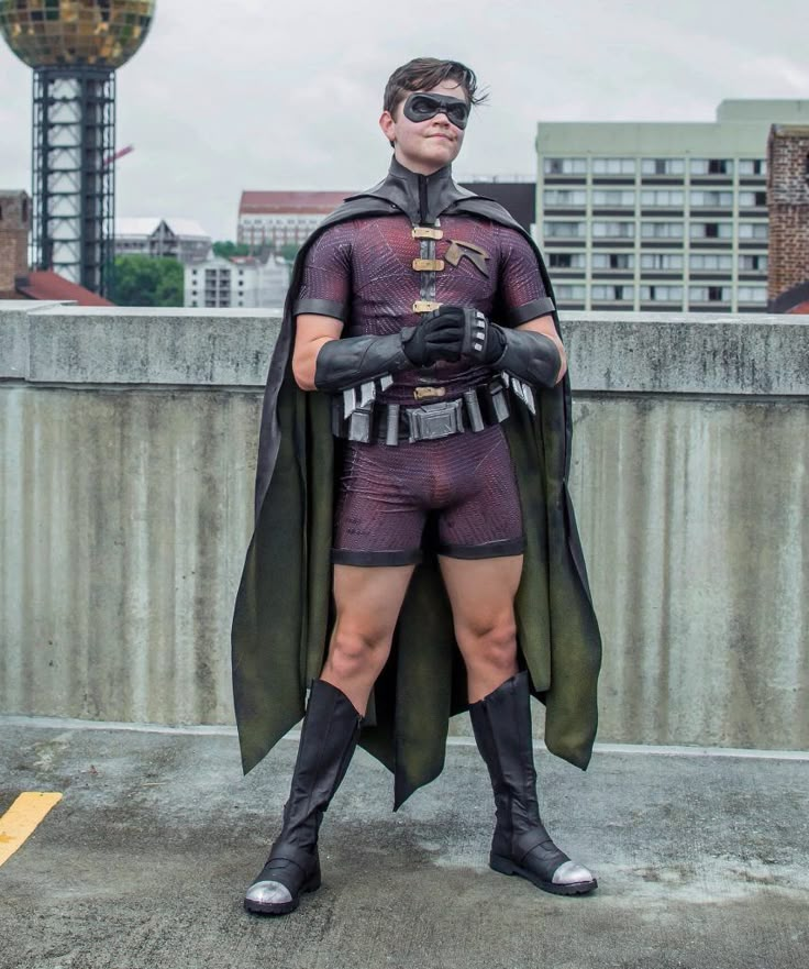 a man dressed as batman standing on top of a cement wall with his hands in his pockets