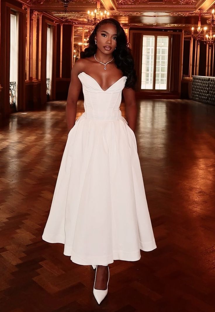 a woman in a white dress standing on a wooden floor