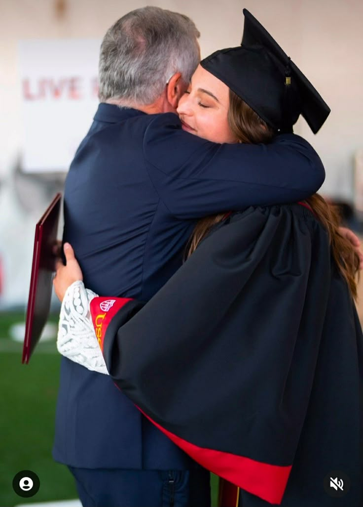 a man and woman hugging each other at graduation