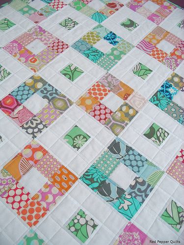 a quilted table topper with colorful squares and flowers on the edges, all in different colors