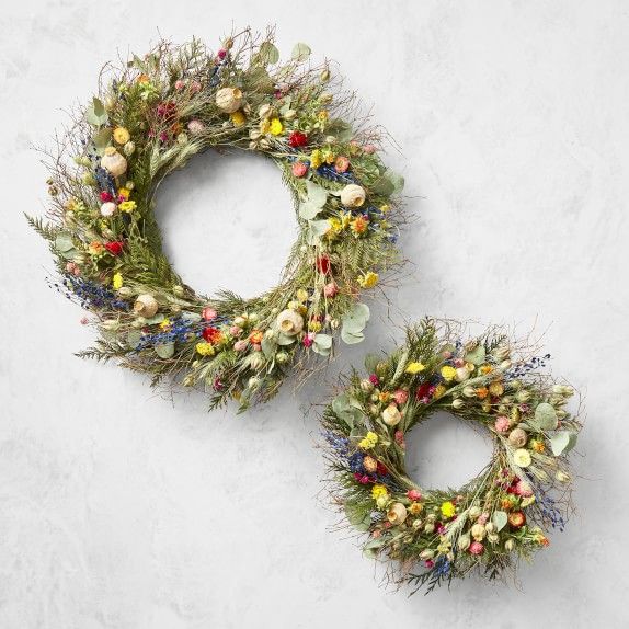 two wreaths sitting next to each other on top of a white surface with flowers