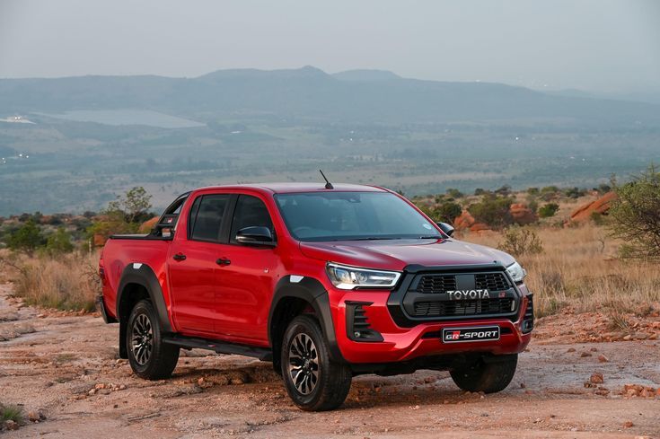 a red truck parked on top of a dirt field