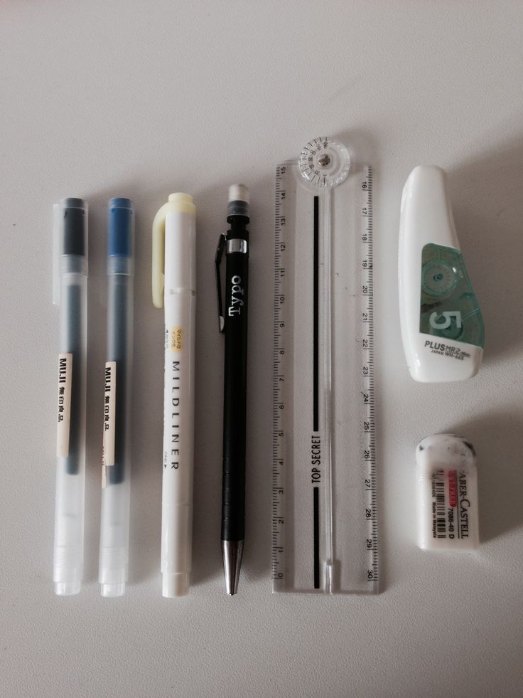 several pens, pencils, and an eraser on a white surface next to each other