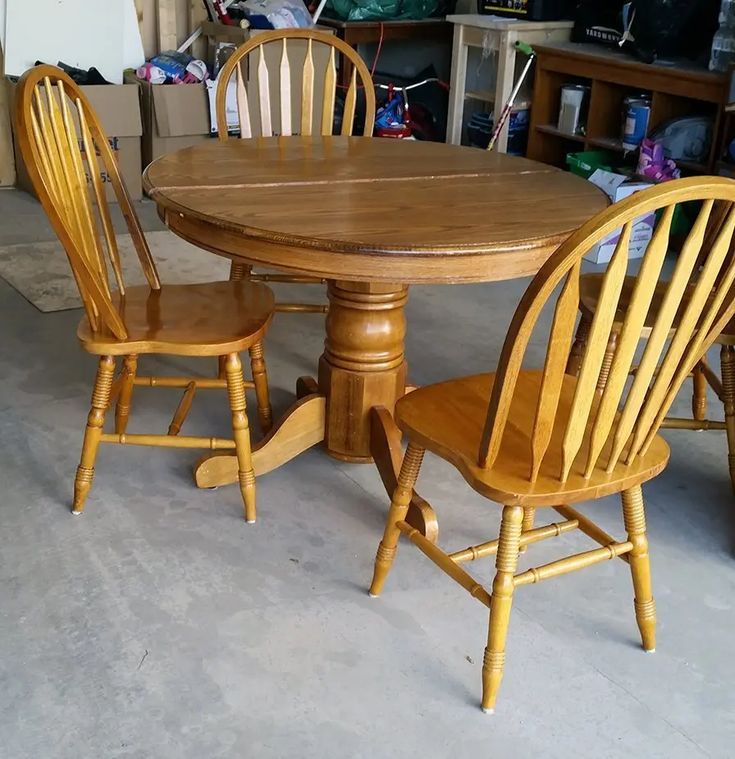 a wooden table with two chairs around it in a room filled with boxes and other items