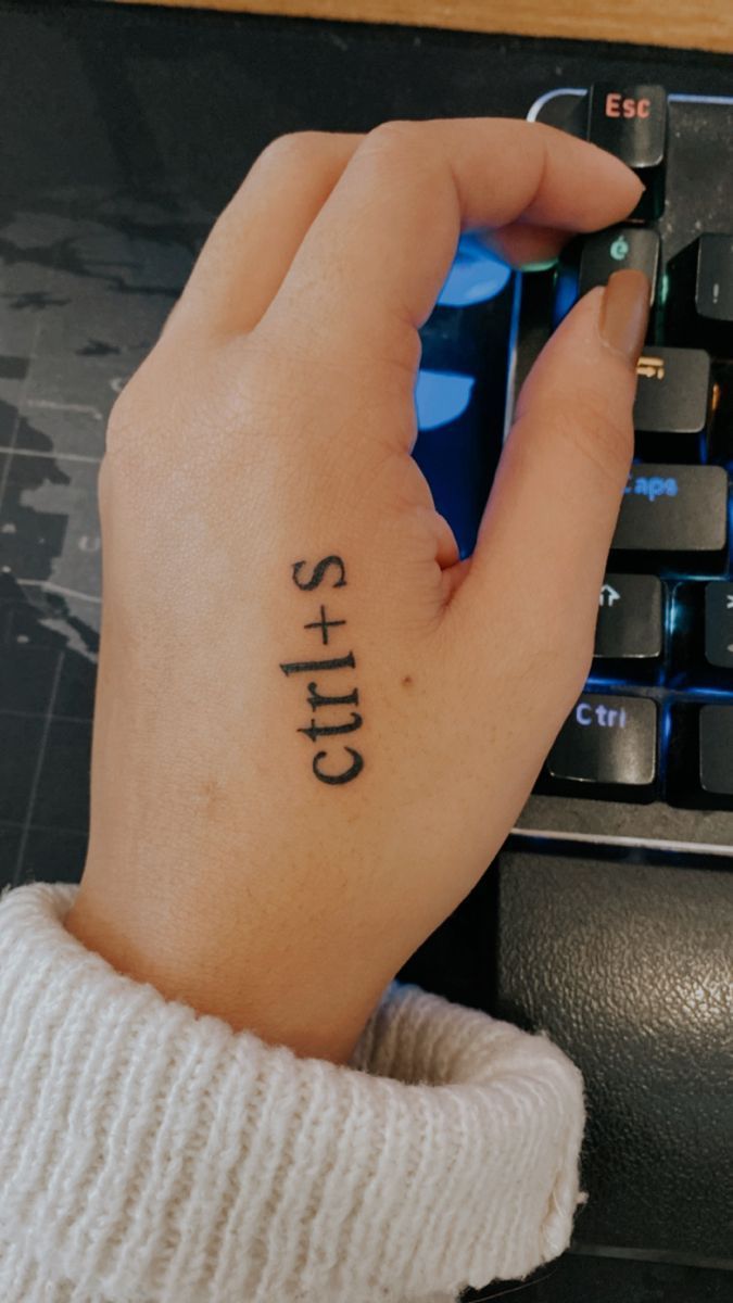 a person with a tattoo on their left hand next to a keyboard