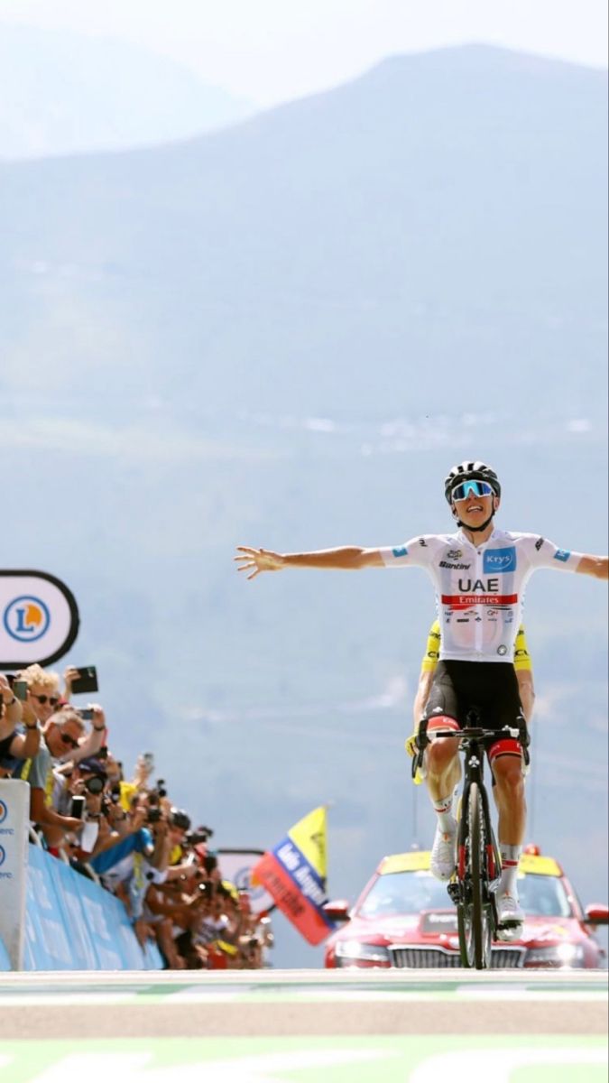 a man riding a bike on top of a race track with his arms outstretched in the air