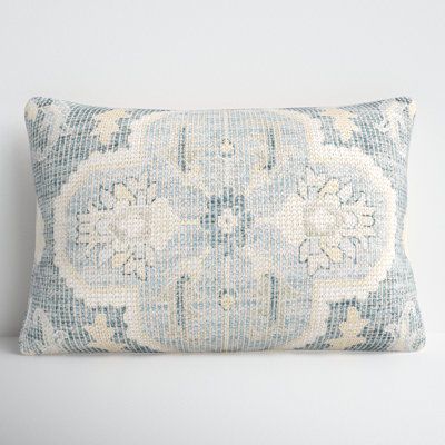 a blue and white pillow with an intricate design on the front, sitting against a wall