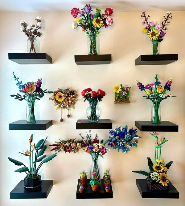 there are many vases with flowers in them on the wall behind each other,