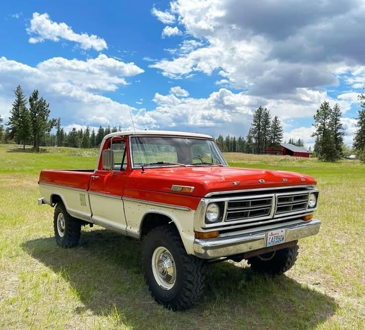 an old red and white truck parked in a field