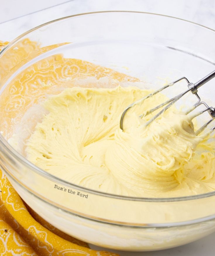 a mixing bowl filled with batter and whisk next to two yellow napkins