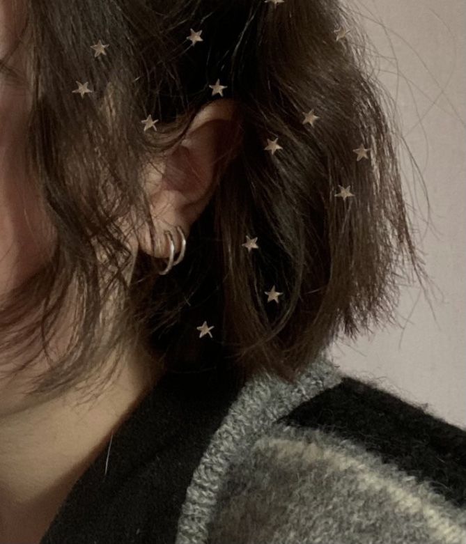 a close up of a person with stars on their hair and ear piercings in the shape of stars