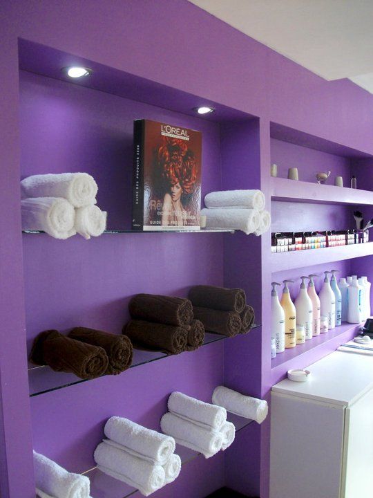 a bathroom with purple walls and shelving filled with lots of white towels on shelves