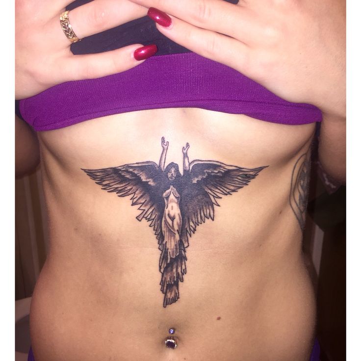 a woman's stomach with a bird tattoo on her side and the bottom part of her abdomen