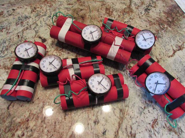 red and black wrapped dynamites with clocks attached to them on a marble counter top