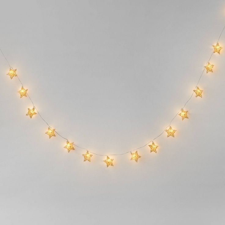 a string of yellow stars is hanging from the side of a white wall with lights on it