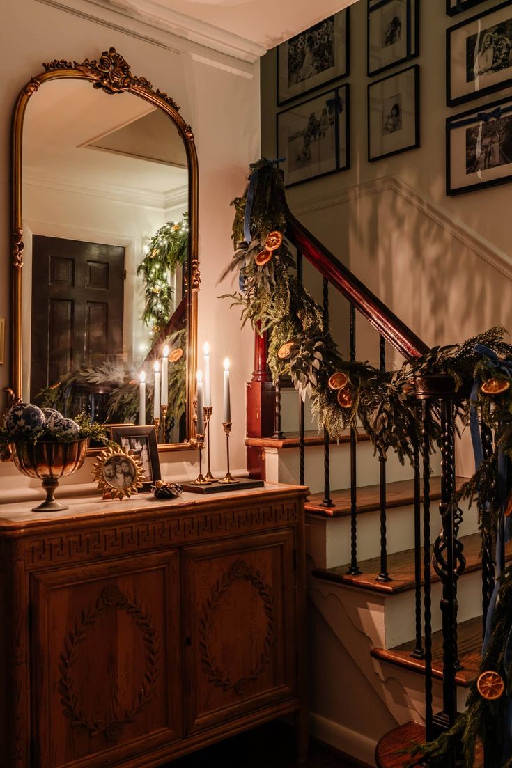 a staircase decorated with greenery and candles next to a mirror on top of a dresser