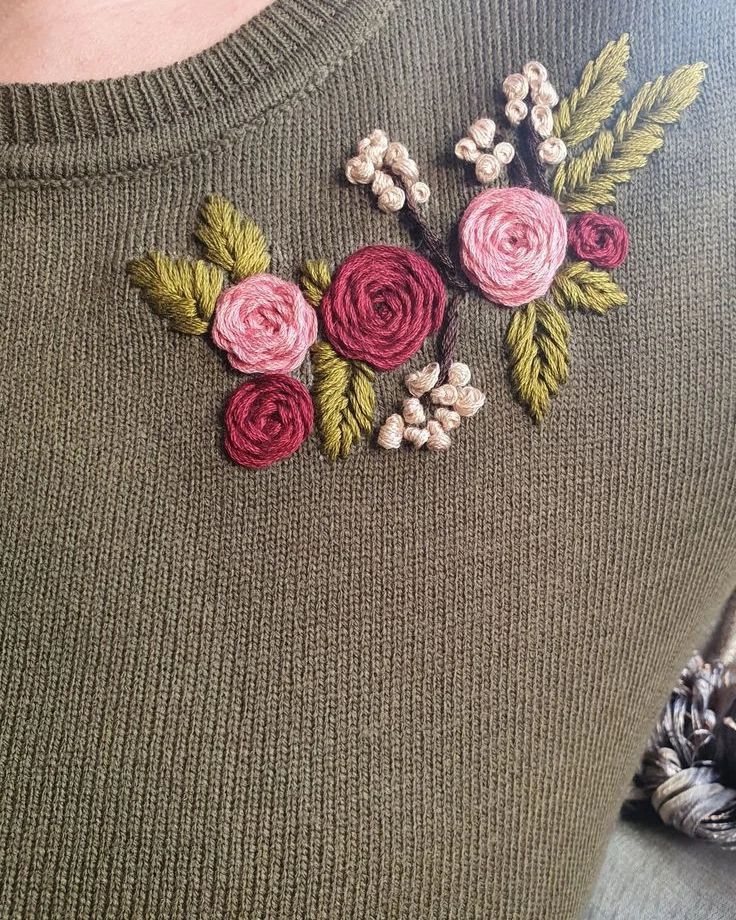 a close up of a person wearing a sweater with flowers embroidered on the back of it