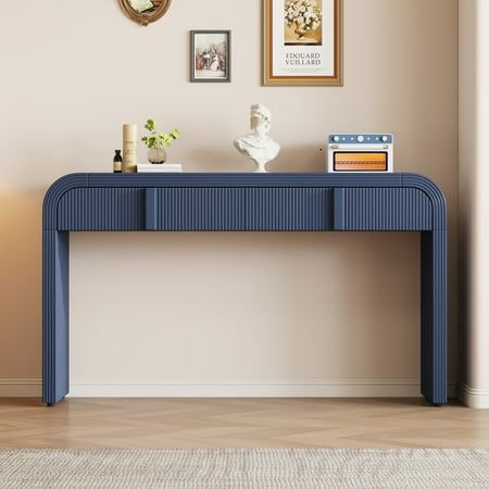 a blue console table sitting in front of a wall with pictures on it and a clock