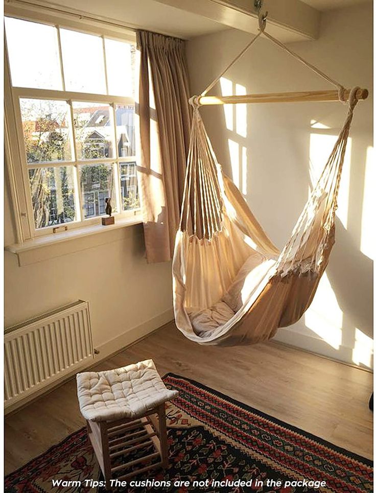 a hammock hanging in the corner of a room with a rug on the floor