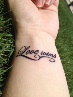 a woman's wrist tattoo with the words love wins on it