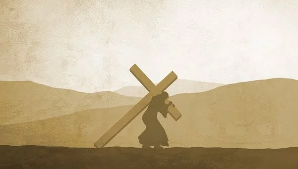 a person carrying a cross in the middle of a field with mountains in the background