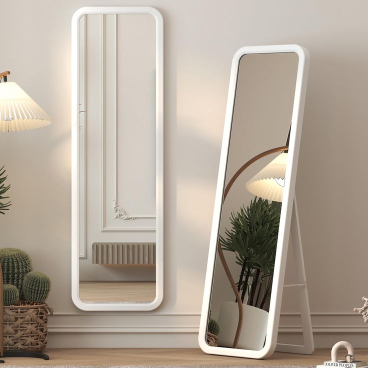 a large white mirror sitting on top of a wooden floor next to a potted plant