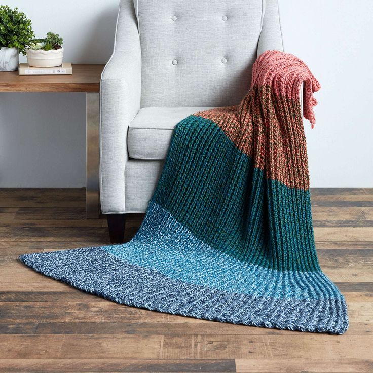 a chair with a blanket on top of it next to a table and potted plant