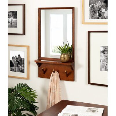 a mirror hanging on the wall next to a table with a potted plant in it