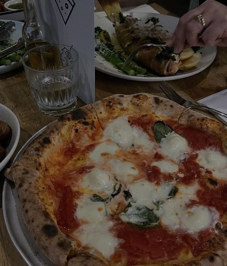 a pizza sitting on top of a white plate covered in sauce and cheese next to other plates