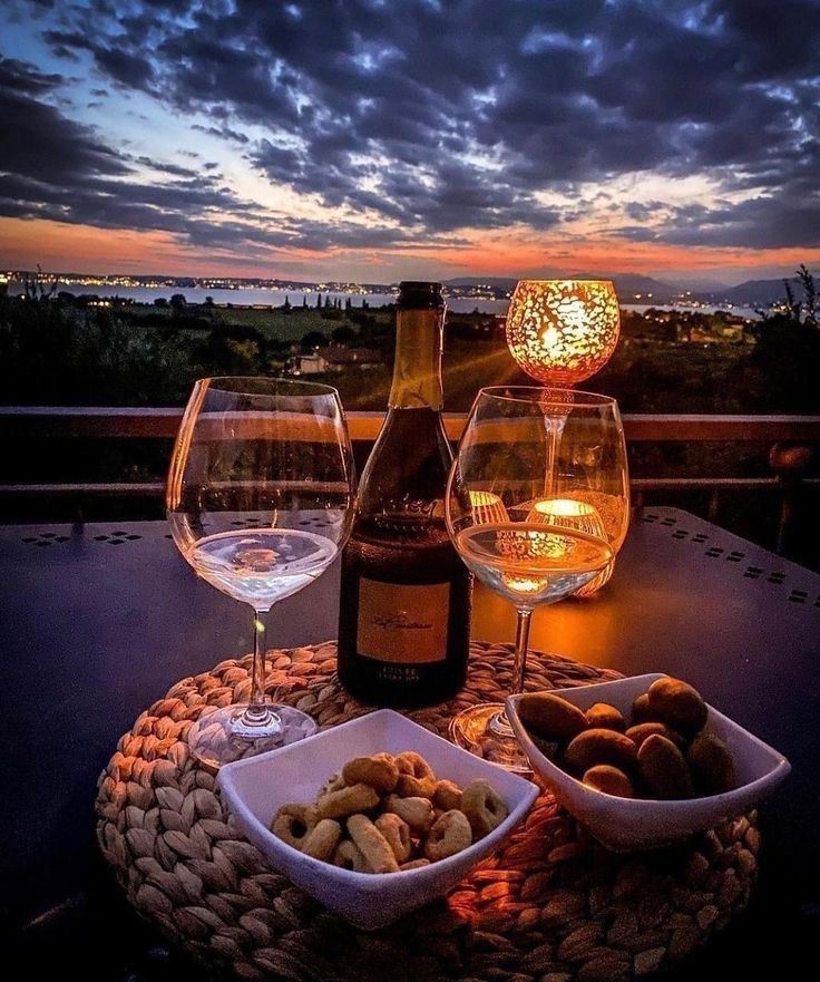 two wine glasses sitting on top of a table next to some food and drink bottles