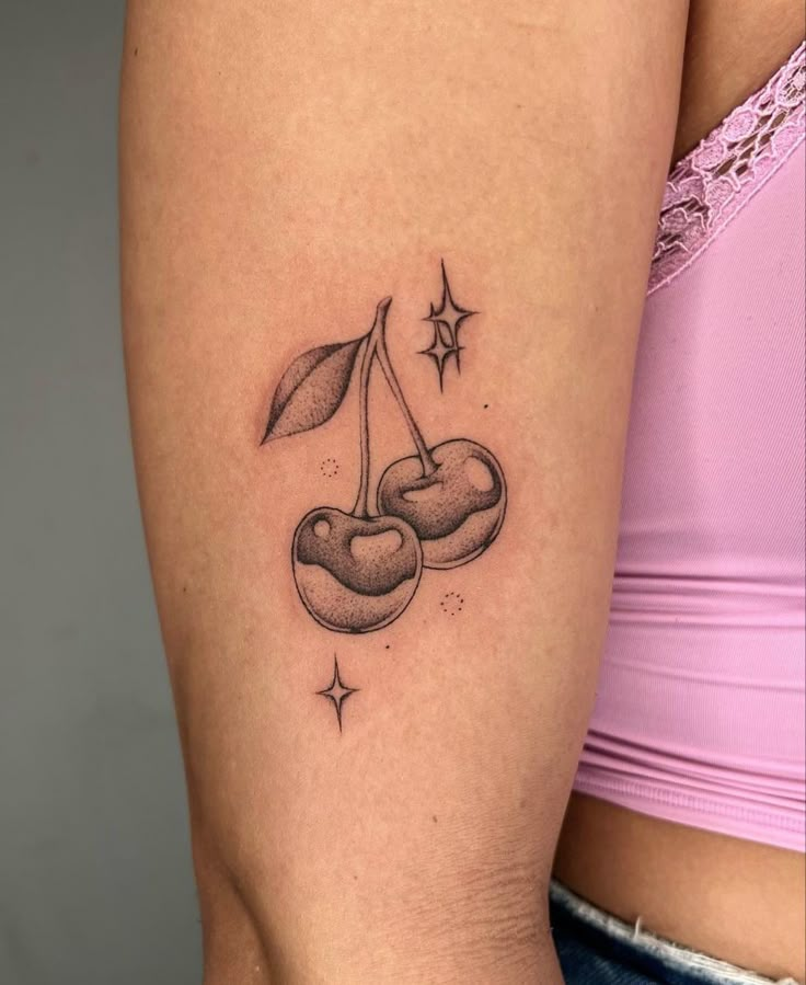 a woman's arm with a small tattoo of two cherries on the side