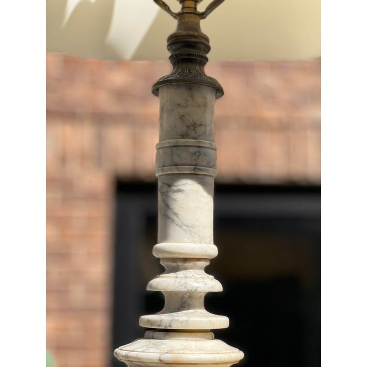 an old fashioned street lamp is standing in front of a brick building