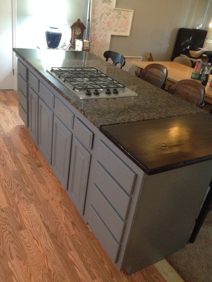 a kitchen with an island and stove top in the middle of it, surrounded by wood flooring