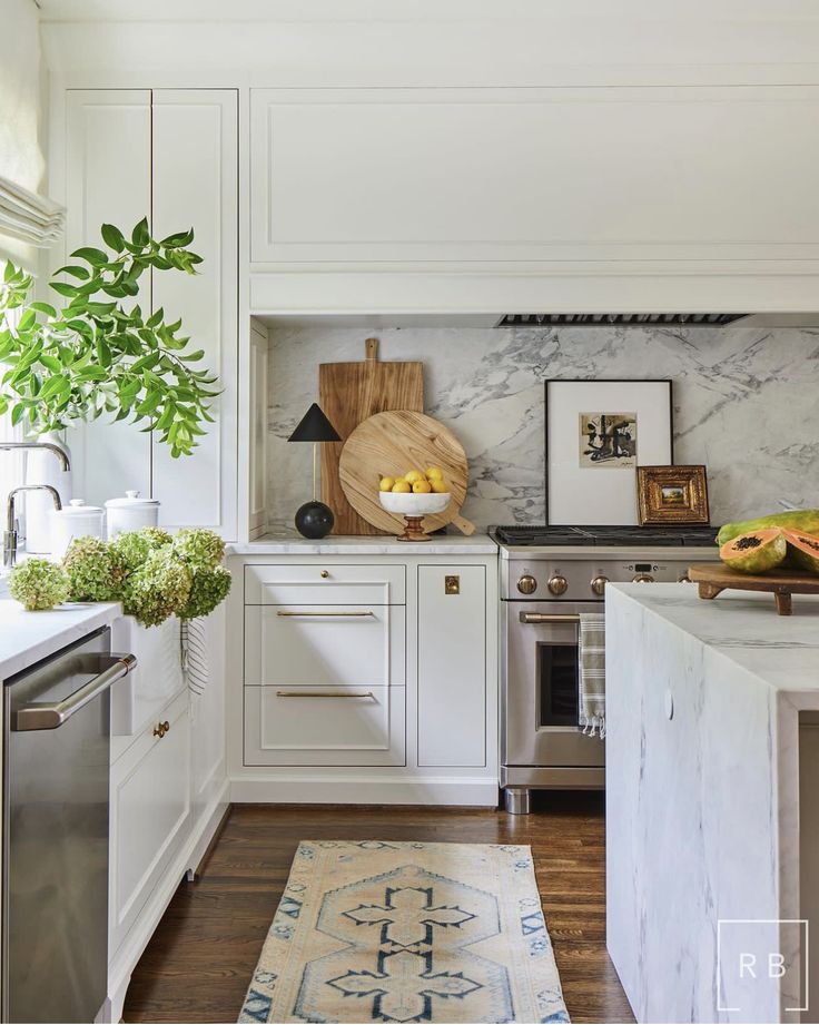 a kitchen with marble counter tops and white cabinets, along with a rug on the floor