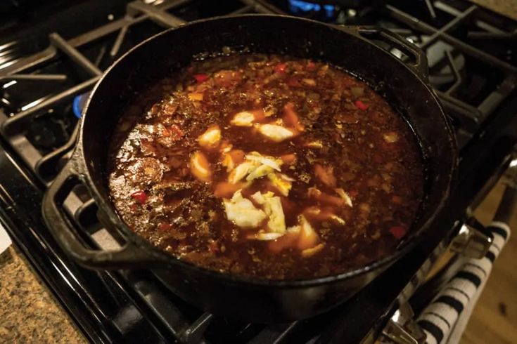 a pot filled with food sitting on top of a gas stovetop next to an oven