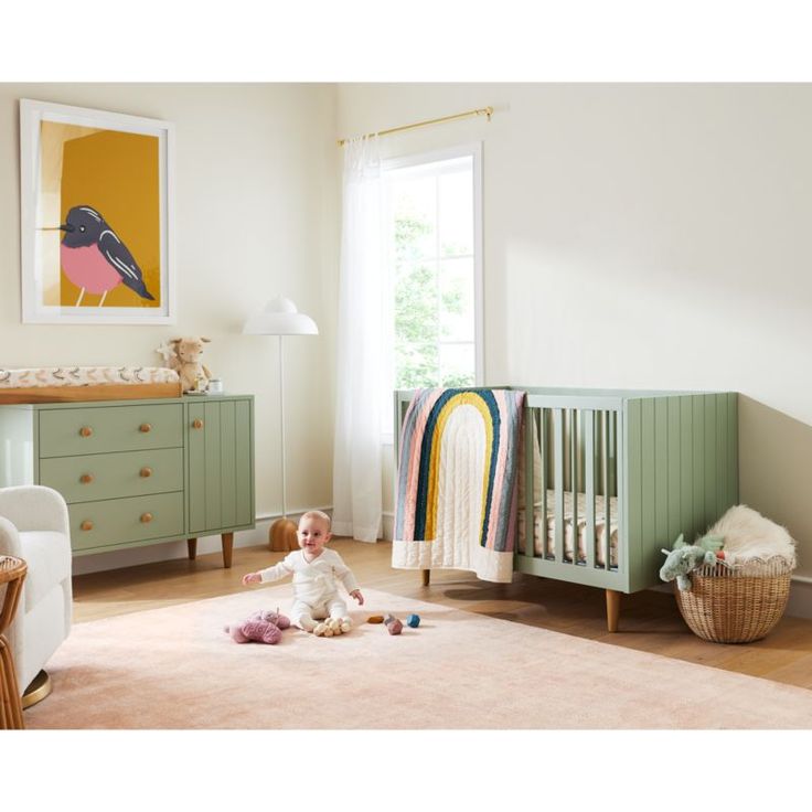 a baby sitting on the floor next to a crib in a room filled with furniture