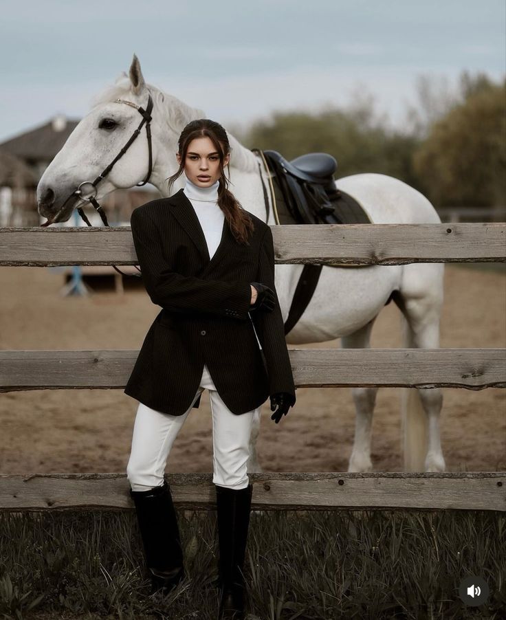 a woman standing next to a white horse