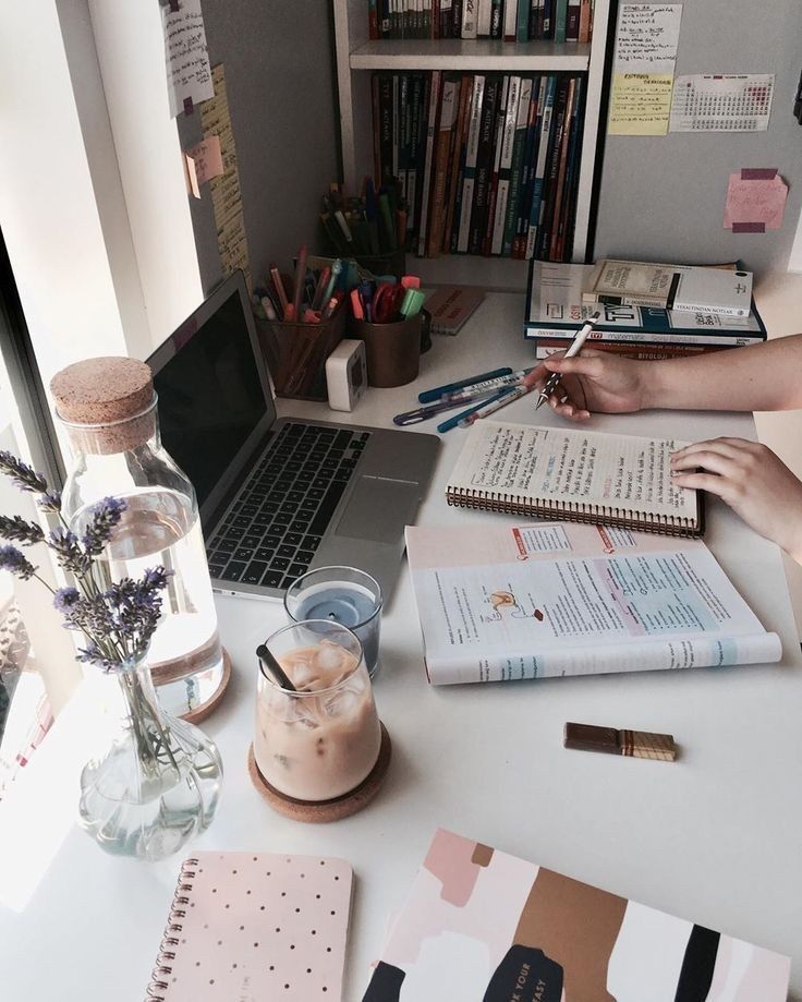 someone is working at their desk with many books and notebooks on the table in front of them