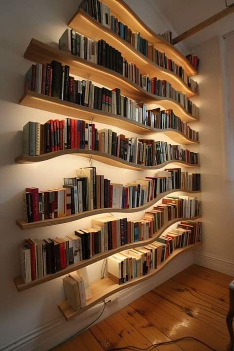 a bookshelf filled with lots of books on top of a wooden floor next to a wall