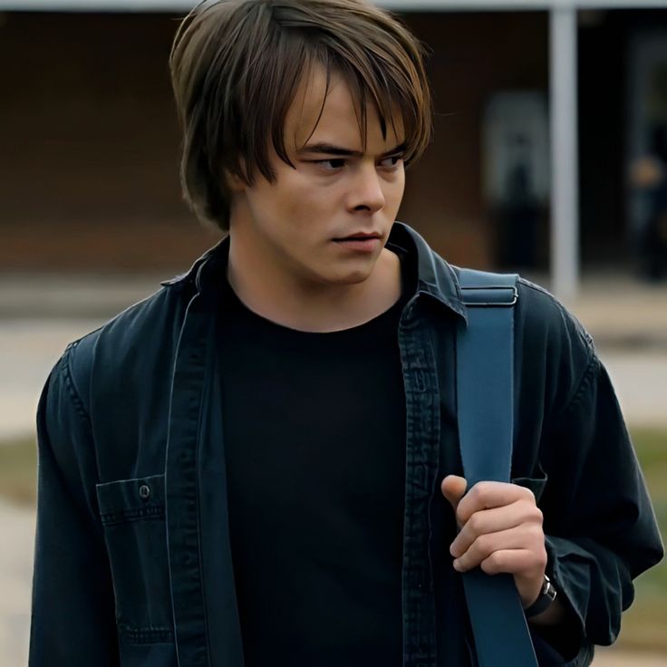 a young man with a black shirt and blue backpack is looking at something in his hand