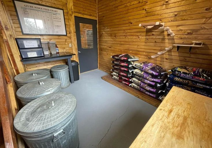 the inside of a wooden building with several barrels and bins on the floor next to each other