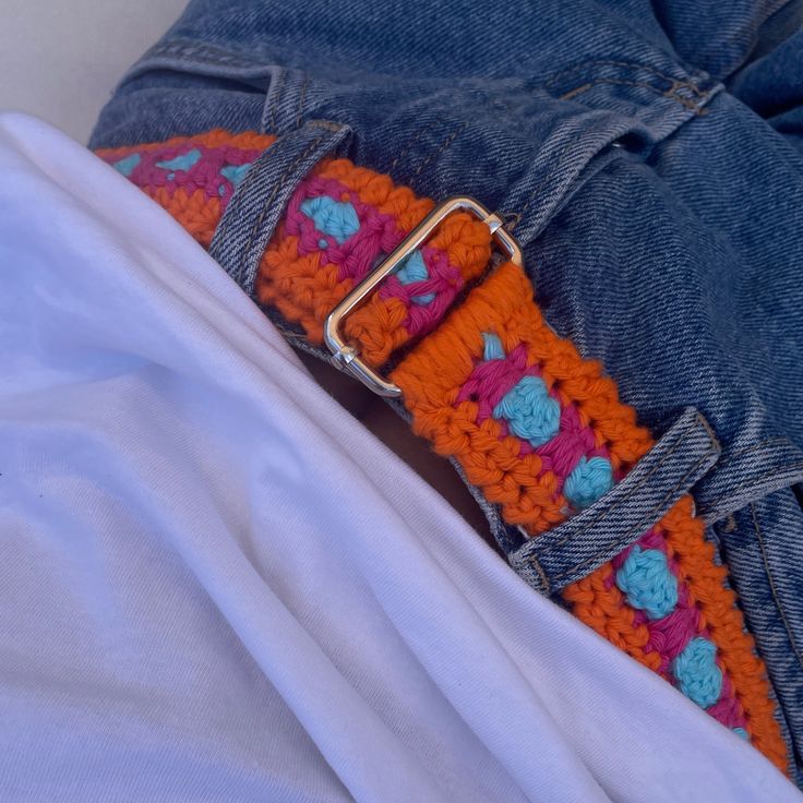 an orange and blue crocheted belt is on someone's jeans