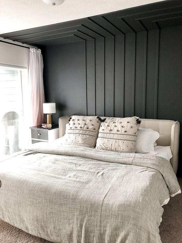 a bedroom with black walls and white bedding