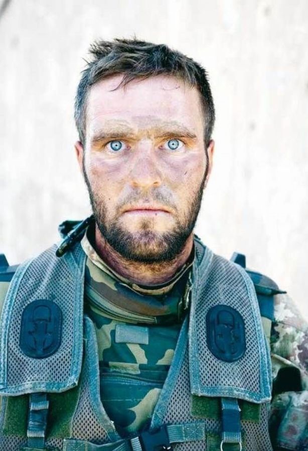 an image of a man with blue eyes and camouflage vest on, looking at the camera