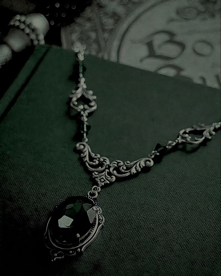 a black and white photo of a green book with a necklace hanging from it's side