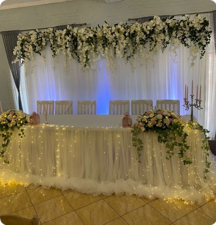 the table is set up with white flowers and greenery for an elegant wedding reception