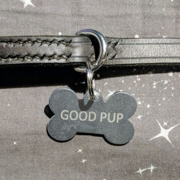 a dog tag that says good pup on it's back end is attached to a black leather leash