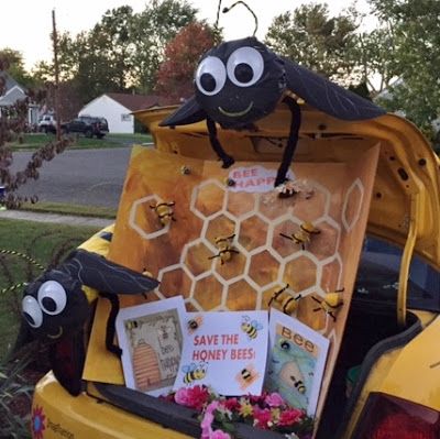 the back of a yellow car with bee decorations on it's trunk and bees in the honeycombs