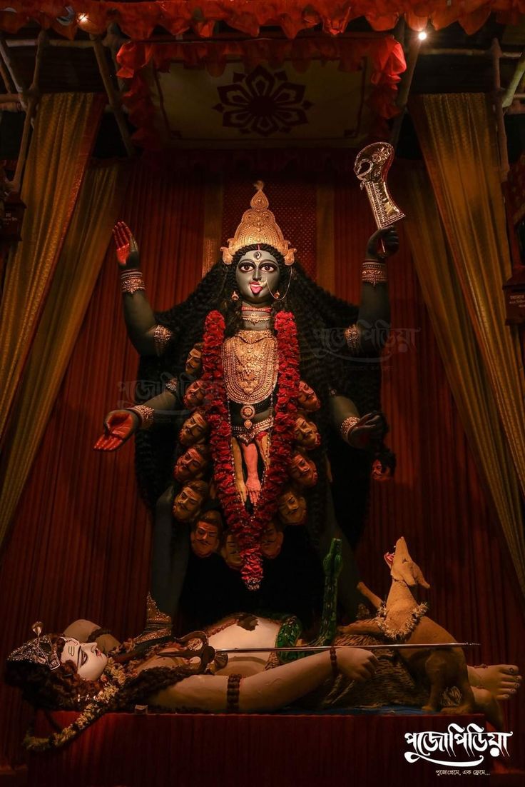 an idol is displayed in the middle of a room with red curtains and drapes